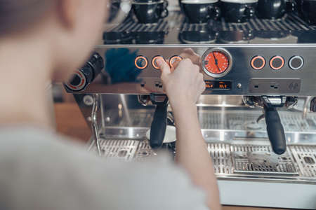 Female barista using modern coffee machine in cafeteriaの写真素材