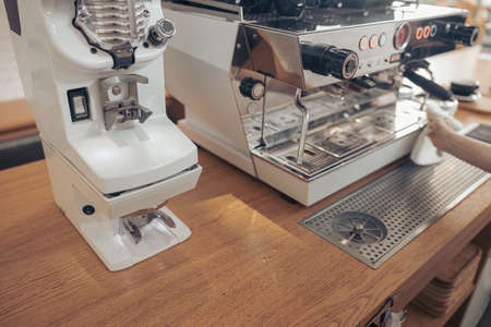 Barista cleaning professional coffee machine in cafeteriaの写真素材