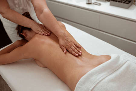 Professional masseuse massaging female back in spa salonの写真素材