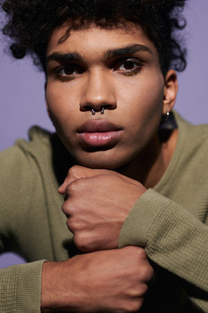 Close up portrait of young afroamerican man face on arms. Sexy transgender male with pirsing in noseの写真素材