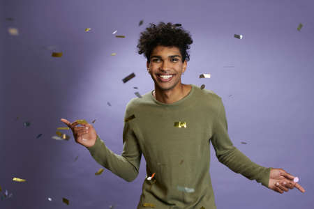 Cheerful young man celebrate dancing on confetti party portrait. Smile and laugh of happy maleの写真素材