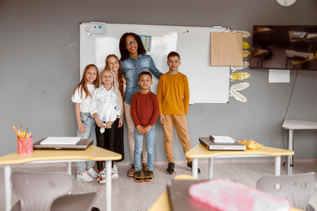 Happy children and a teacher posing in class togetherの写真素材