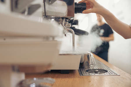 Female barista using coffee machine in cafeteriaの写真素材