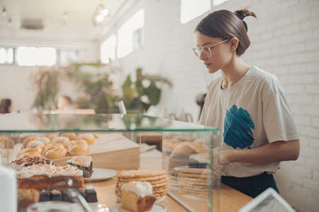Charming young woman working in bakery shopの写真素材