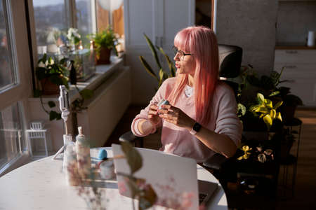 Woman beauty blogger shoots new video at table with cosmetic products and laptopの写真素材