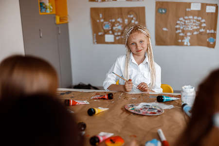 Cute little girl sitting at a desk at a drawing lessonの写真素材