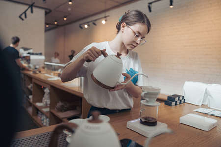 Charming young woman making filter coffee in cafeteriaの写真素材