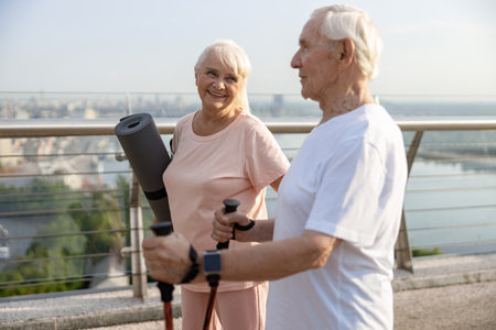 Sportive mature woman and man stand on bridge in modern city at sunset lightの写真素材