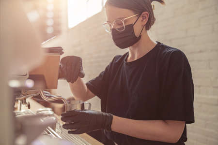Cute woman working with coffee machine in cafeteriaの写真素材