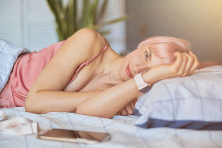 Pretty woman awakes in modern comfortable bed in hotel roomの写真素材