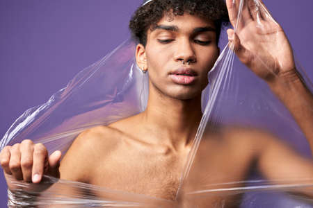 Close up horizontal portrait of young man break-up plastic bag with hands. Feels freedom transgenderの写真素材