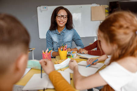 Young teacher talking with kids during the lesson in the classroomの写真素材