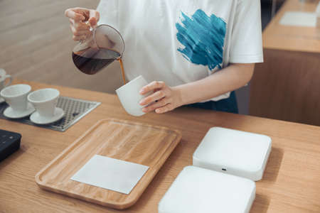 Female barista pouring coffee into cup in cafeteriaの写真素材