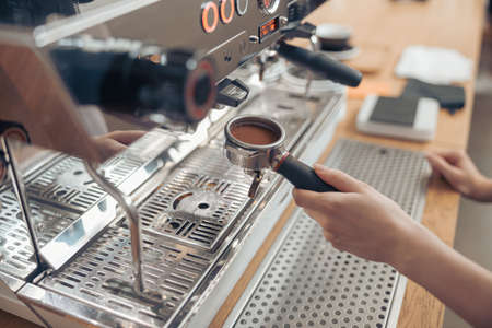 Female barista using modern coffee machine in cafeteriaの写真素材