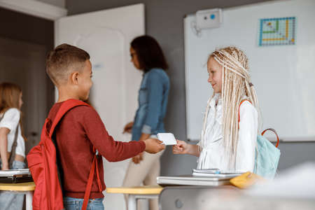 Happy two kids with backpacks standing in classの写真素材