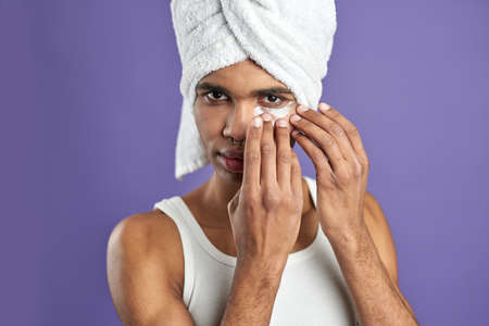 Close up portrait of young african american man use gel eye anti-wrinkle patche in bath towelの写真素材