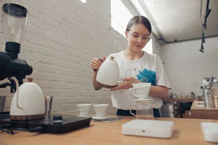Charming female barista making filter coffee in cafeteriaの写真素材