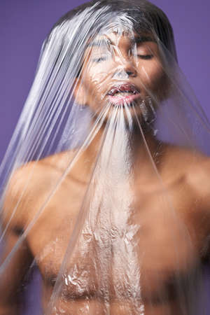 Portrait of young man with plastic bag on head stop breathe with open mouth. Scared transgender maleの写真素材