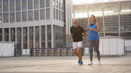 Sportive middle aged couple jogging together in the morning while training outdoorsの写真素材