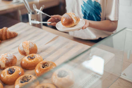 Female hand holding plate with delicious pastryの写真素材