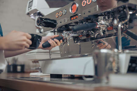 Female barista using professional coffee machine at workの写真素材