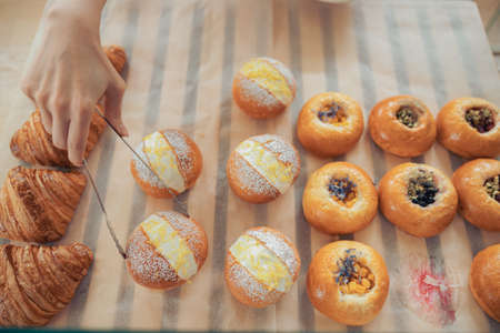Female hand taking cake from display showcase in bakery shopの写真素材