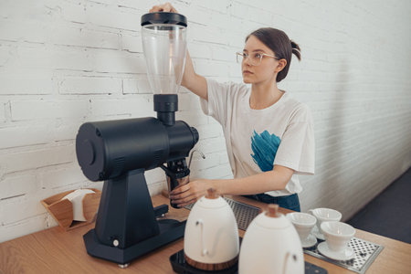 Nice female barista using professional coffee machine in cafeteriaの写真素材