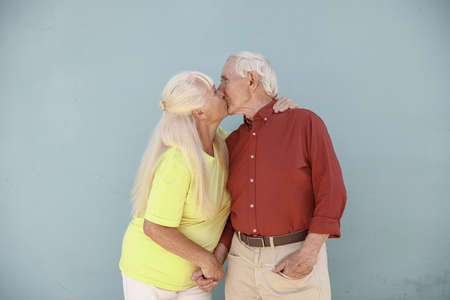 Adorable senior pair of sweethearts kisses on light grey backgroundの写真素材