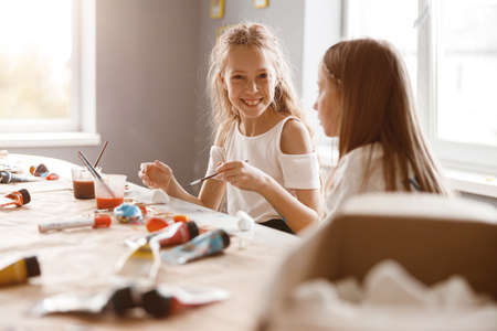 Two girlfriends talking while painting with watercolors at schoolの写真素材