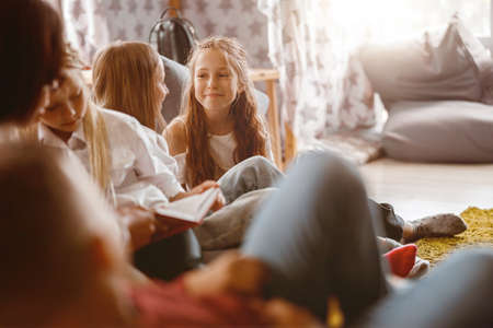 Smiling girls chatting during a lesson at schoolの写真素材