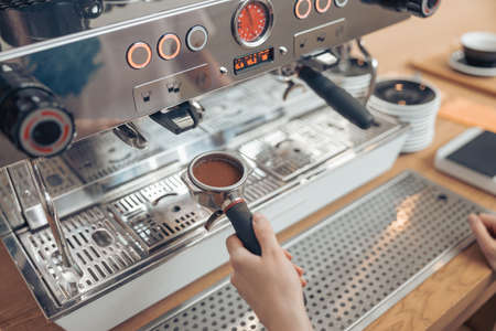 Female barista using professional coffee machine in cafeteriaの写真素材