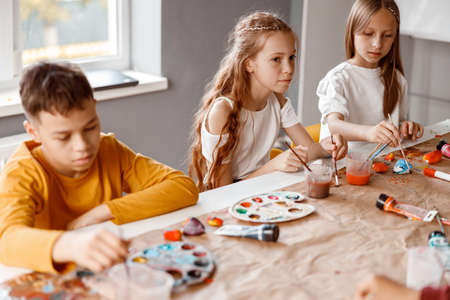 Kids painting on paper with colorful paints in schoolの写真素材