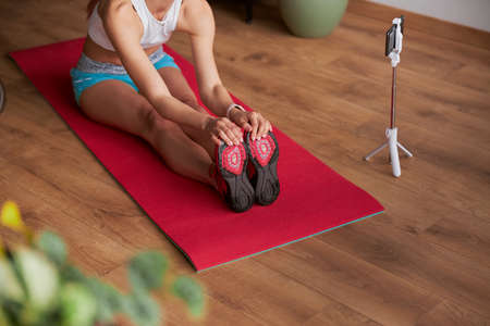 Flexible lady shoots nw video doing forward bend while sitting on floorの写真素材