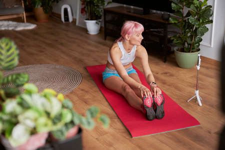 Woman blogger shoots new video doing forward bend while sitting on matの写真素材
