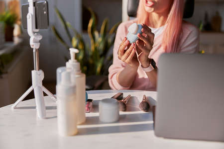 Beauty blogger shows electric facial cleansing brush recording video tutorial at tableの写真素材