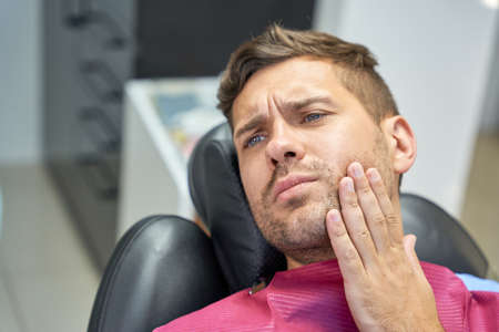 Brunette man suffering from dental pain in clinicの写真素材