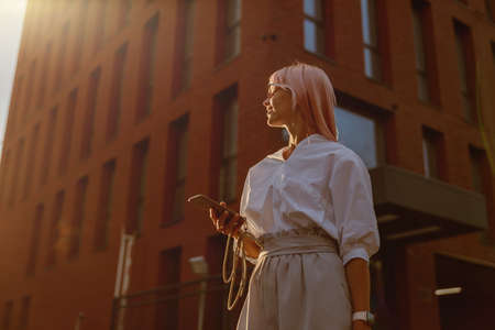 Young woman with mobile phone standing on the streetの写真素材
