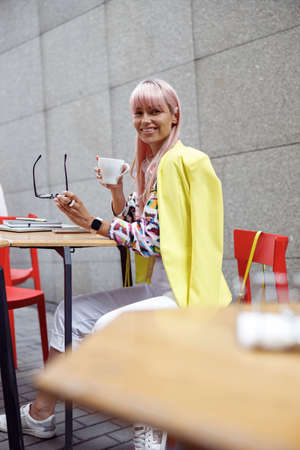 Female taking off glasses and smiling to camera with coffeeの写真素材