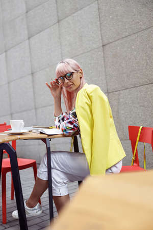 Female turning to camera while adjusting glasses outdoorsの写真素材