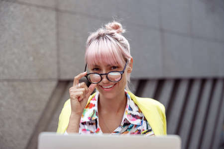 Cheerful lady lowering glasses from eyes and looking to cameraの写真素材