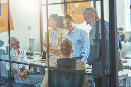 Working in team. Group of happy multi ethnic business people discussing work and sharing fresh ideas while having a meeting in the modern officeの写真素材