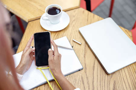 Adult using smartphone over noteapd on tableの写真素材