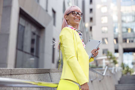 Delighted woman with laptop smiling at street staircaseの写真素材