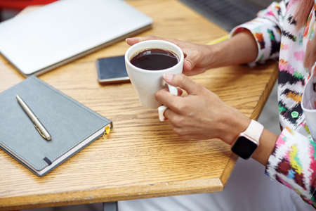 Cup of coffee held by person in street cafeの写真素材
