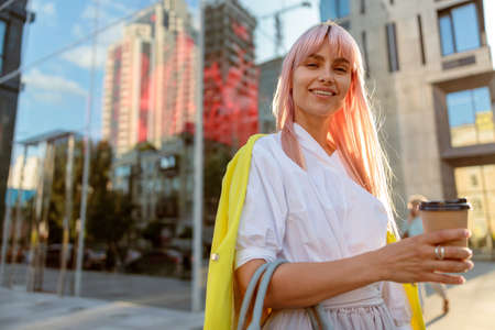Joyful woman standing on the street and holding coffee cupの写真素材
