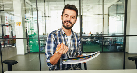Expressive brunette man pointing pencil at the camera and smilingの写真素材