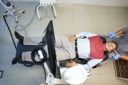 Full-length photo of male patient in dentist chair