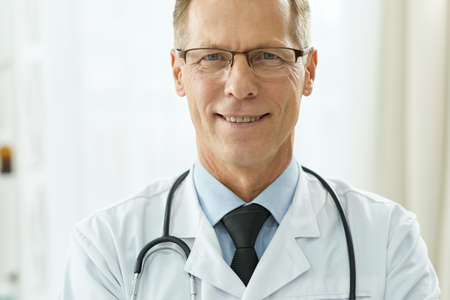 Cheerful male doctor standing against white backgroundの写真素材