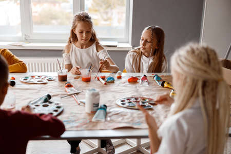 Classmates painting on paper with colorful paintsの写真素材