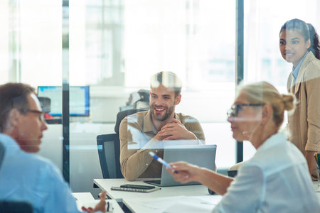 Group of multiracial business people sitting in board room in the modern office and discussing something while having a meetingの写真素材